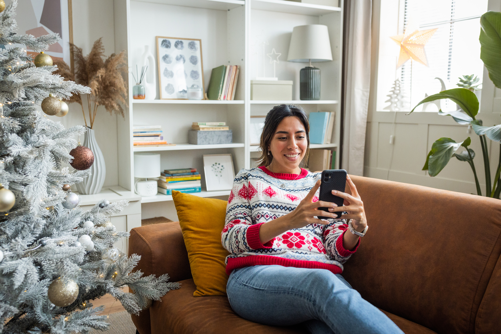 Young woman on couch smiling at cellphone